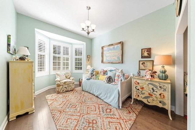 bedroom with an inviting chandelier, baseboards, and wood finished floors