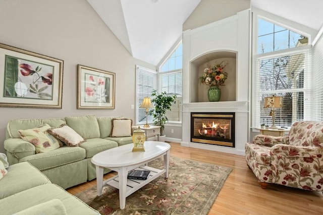 living room with high vaulted ceiling, a large fireplace, and light wood-type flooring