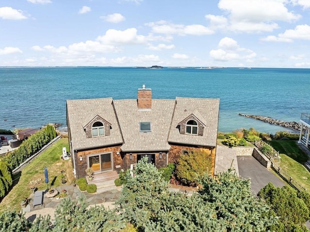 exterior space featuring brick siding, a chimney, and a water view