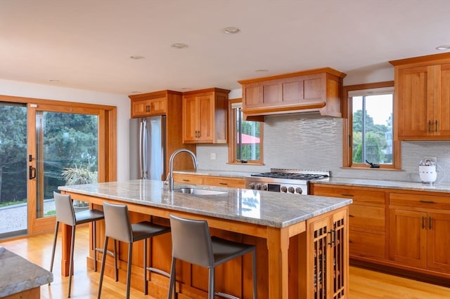 kitchen featuring a kitchen island with sink, appliances with stainless steel finishes, backsplash, and a healthy amount of sunlight