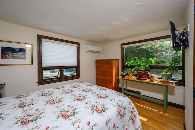 bedroom with a wall mounted air conditioner and wood-type flooring