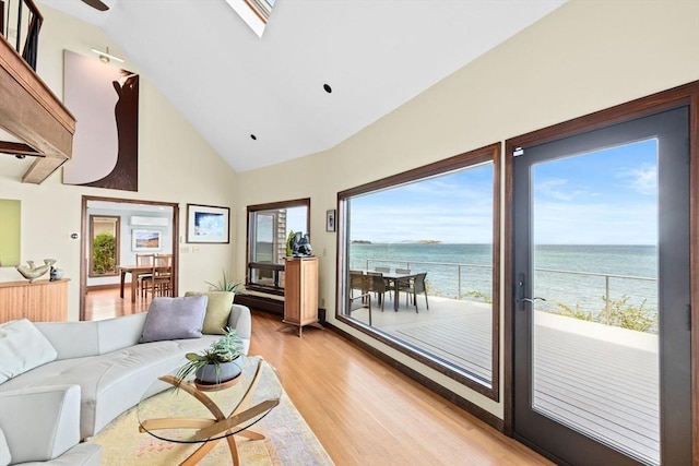 living area with light wood-style flooring, high vaulted ceiling, and a water view