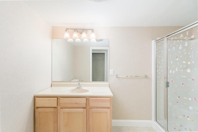 bathroom with a stall shower, vanity, and baseboards