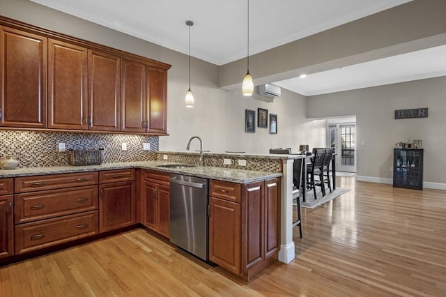 kitchen with kitchen peninsula, light stone counters, sink, dishwasher, and hanging light fixtures