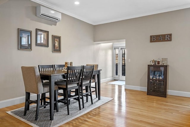 dining room featuring a wall mounted AC, crown molding, and light wood-type flooring