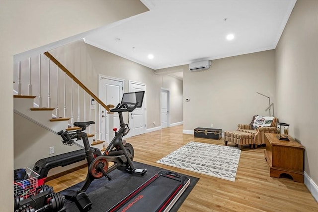 exercise room with hardwood / wood-style flooring, a wall mounted AC, and ornamental molding