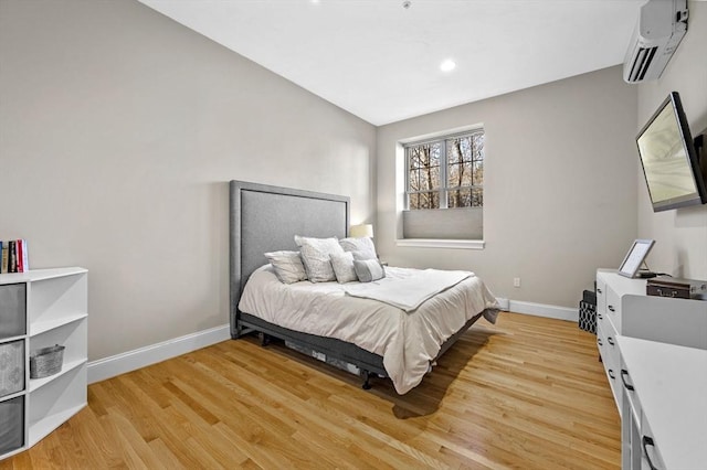 bedroom with a wall unit AC, vaulted ceiling, and light wood-type flooring