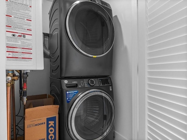 laundry room featuring laundry area, water heater, and stacked washer / drying machine