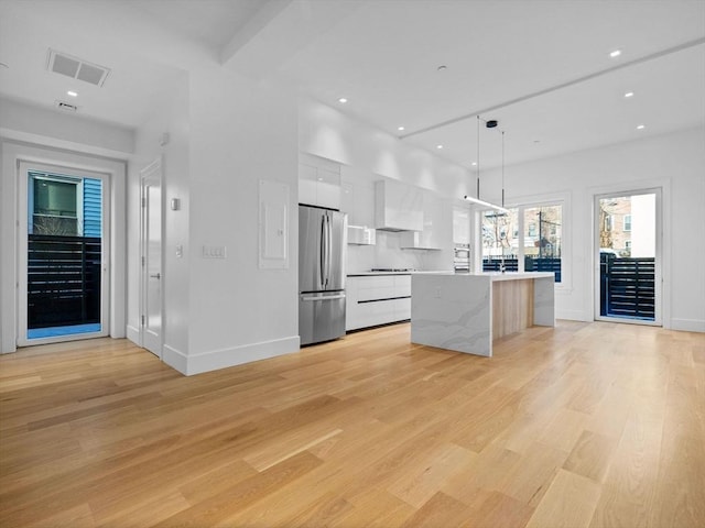 kitchen with visible vents, white cabinetry, light wood-type flooring, modern cabinets, and stainless steel fridge