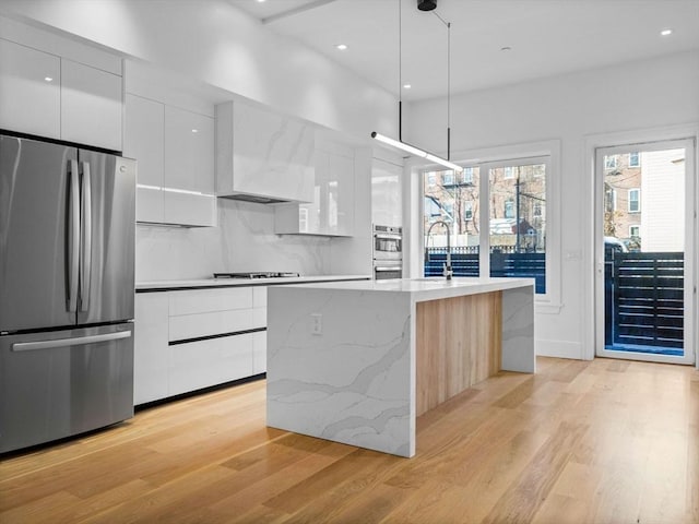 kitchen with appliances with stainless steel finishes, modern cabinets, wall chimney range hood, and white cabinetry