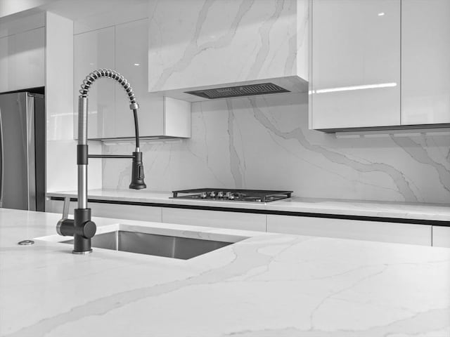 room details featuring light stone countertops, white cabinets, a sink, and freestanding refrigerator