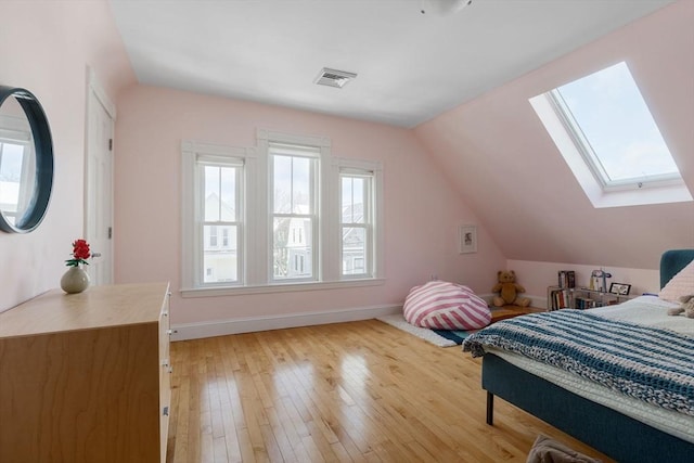 bedroom featuring lofted ceiling with skylight, visible vents, light wood-style flooring, and baseboards