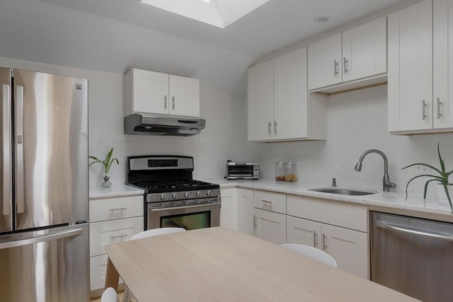 kitchen with under cabinet range hood, a sink, tasteful backsplash, stainless steel appliances, and white cabinets