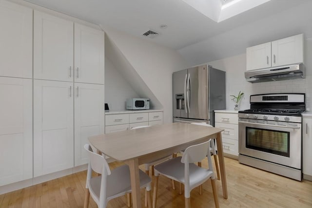 kitchen featuring visible vents, under cabinet range hood, light wood-type flooring, appliances with stainless steel finishes, and white cabinets