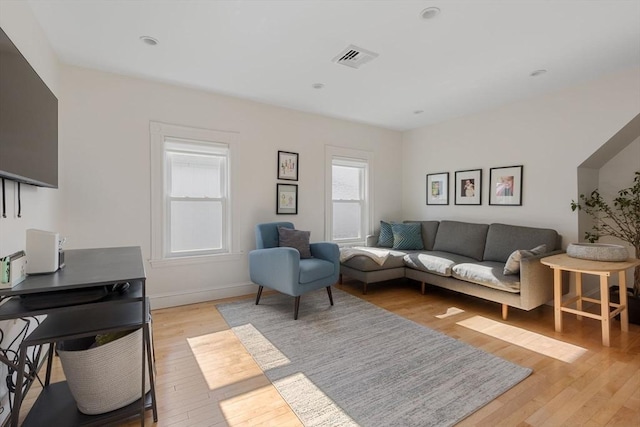 living area featuring baseboards, visible vents, and light wood finished floors