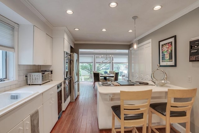 kitchen featuring ornamental molding, pendant lighting, white cabinets, and a kitchen bar