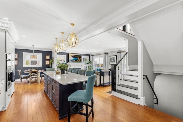 kitchen featuring a breakfast bar, white cabinets, hanging light fixtures, a center island, and light hardwood / wood-style flooring