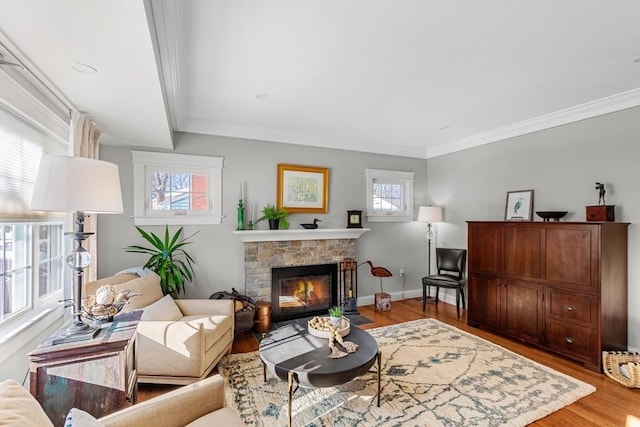 living room featuring ornamental molding, a healthy amount of sunlight, a fireplace, and light wood-type flooring