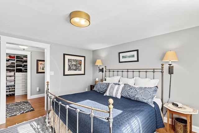 bedroom with hardwood / wood-style flooring and a walk in closet