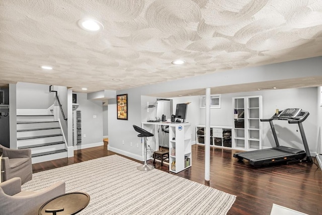 workout room featuring dark wood-type flooring and a textured ceiling