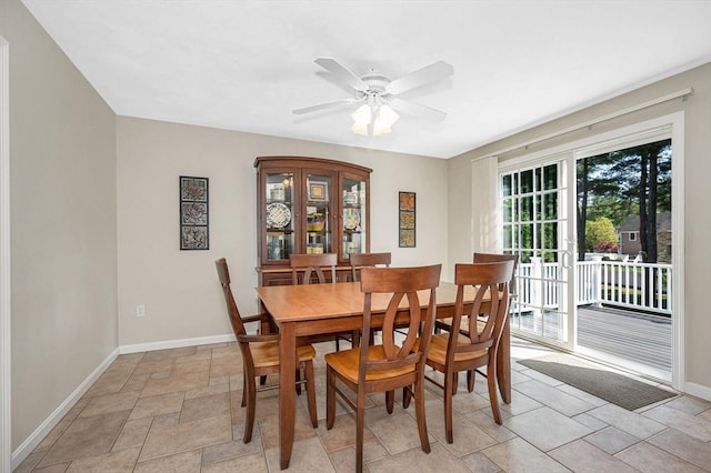 dining room featuring baseboards, light stone finish floors, and ceiling fan