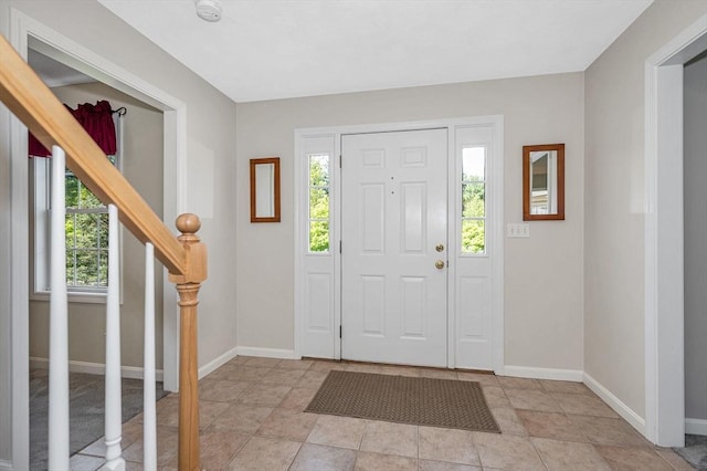 foyer entrance with stairway and baseboards