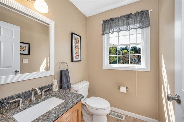 half bath with toilet, vanity, baseboards, and tile patterned flooring