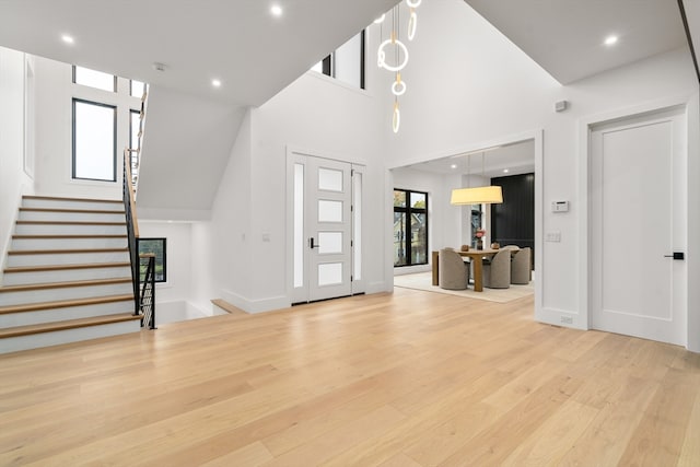 foyer entrance featuring a towering ceiling and light hardwood / wood-style floors