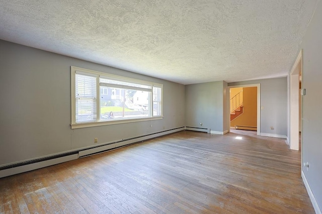 unfurnished room with hardwood / wood-style flooring, stairs, baseboards, a textured ceiling, and a baseboard heating unit