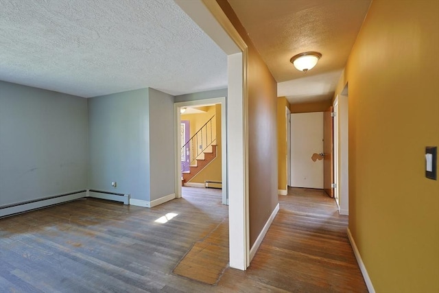 corridor featuring wood finished floors, a textured ceiling, stairs, a baseboard radiator, and baseboards