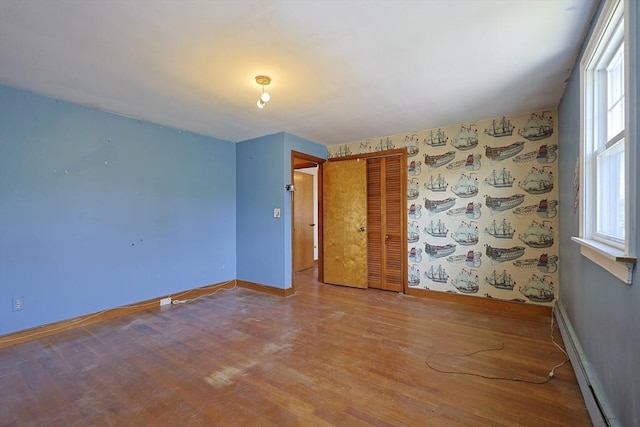 spare room with baseboards, a baseboard radiator, and wood finished floors