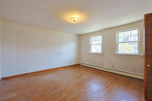 empty room with a baseboard radiator, wood-type flooring, and baseboards