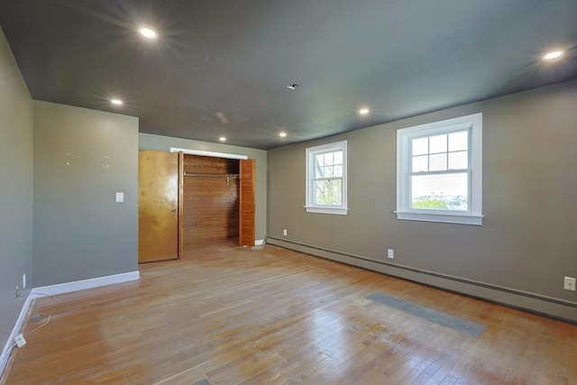 unfurnished room featuring baseboards, baseboard heating, light wood-style flooring, and recessed lighting