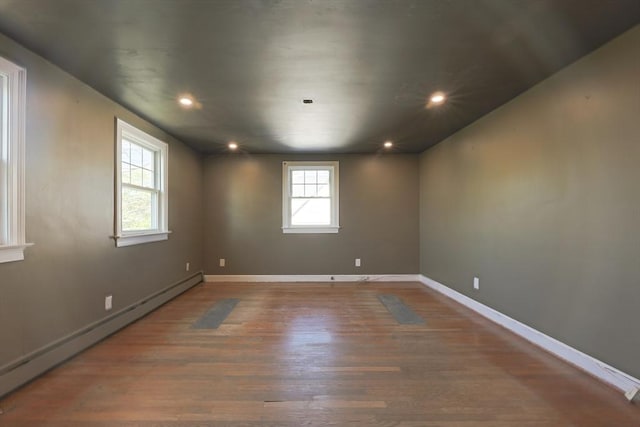 unfurnished room featuring baseboard heating, wood finished floors, recessed lighting, and baseboards