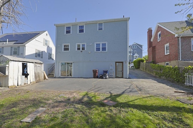 back of property with a storage unit, an outbuilding, fence, and a residential view