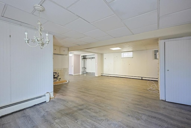 basement with a baseboard radiator, wood finished floors, a chandelier, and wood walls