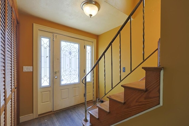 foyer entrance featuring dark wood-style flooring, stairs, and baseboards