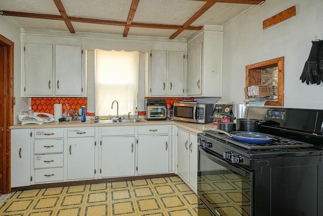 kitchen featuring a textured ceiling, electric range, white cabinetry, and sink