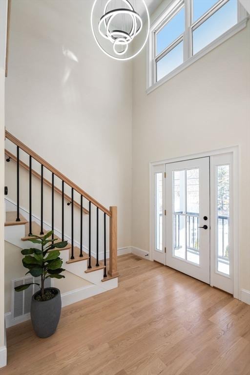 foyer entrance featuring visible vents, plenty of natural light, stairway, and wood finished floors