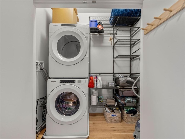 laundry area featuring laundry area, stacked washer and clothes dryer, and wood finished floors
