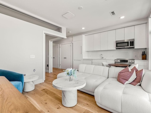 living room featuring recessed lighting, visible vents, and light wood-style flooring