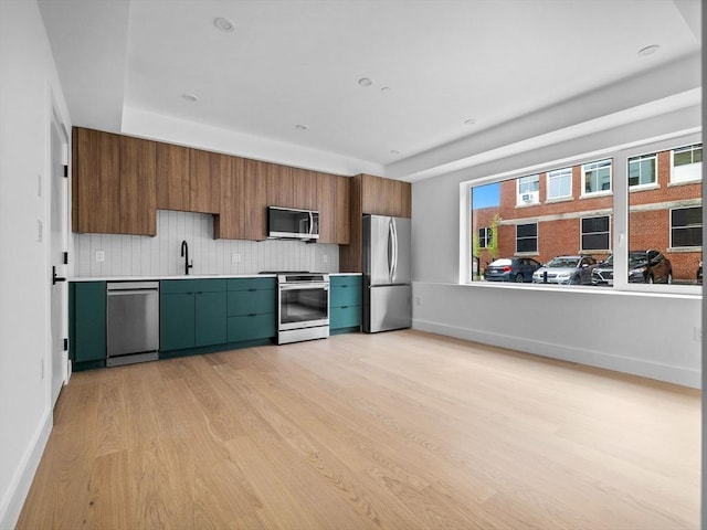 27 Dixwell Unit 1, Boston, MA 02119 - kitchen featuring appliances with stainless steel finishes, light wood-style flooring, tasteful backsplash, light countertops, and a sink