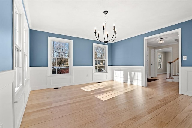 unfurnished dining area featuring ornamental molding, a chandelier, and light wood-type flooring