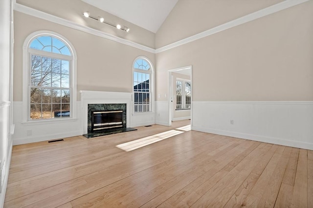 unfurnished living room with high vaulted ceiling, a fireplace, and light hardwood / wood-style floors