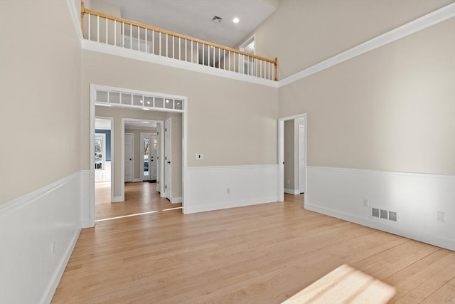 spare room featuring light hardwood / wood-style floors and a high ceiling