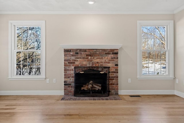 unfurnished living room featuring wood-type flooring, crown molding, a fireplace, and a healthy amount of sunlight