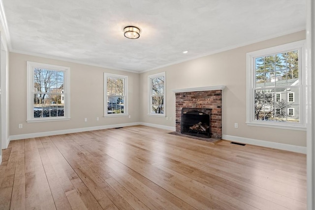 unfurnished living room featuring plenty of natural light, light hardwood / wood-style floors, and a brick fireplace