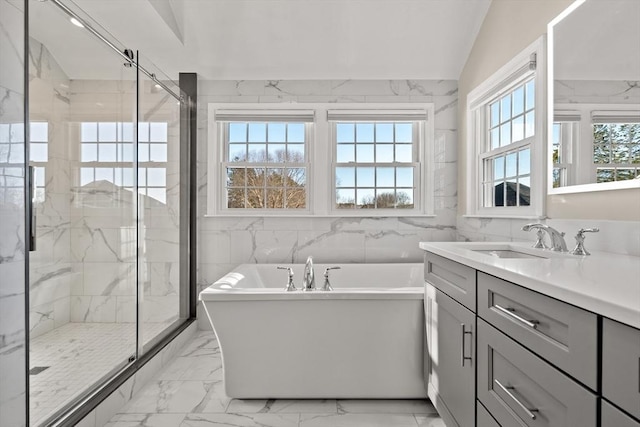 bathroom featuring plus walk in shower, a healthy amount of sunlight, and vanity