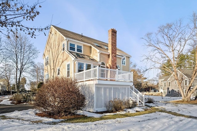 snow covered rear of property featuring a wooden deck