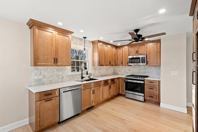 kitchen featuring sink, light hardwood / wood-style flooring, appliances with stainless steel finishes, backsplash, and hanging light fixtures